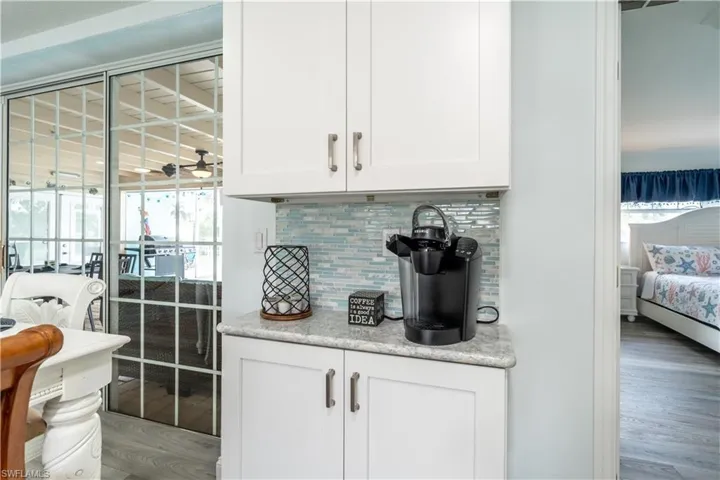 Bar area featuring white cabinets, wood finished floors, decorative backsplash, and healthy amount of natural light