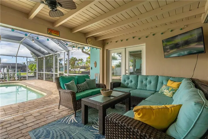 Sunroom featuring ceiling fan, a patio, an outdoor living space, and beam ceiling