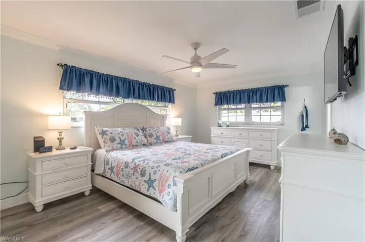 Bedroom with ornamental molding, wood finished floors, and ceiling fan