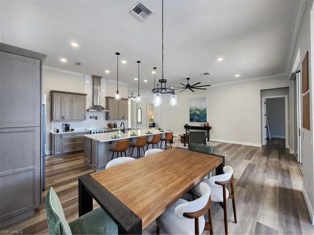 Dining room with dark wood-style flooring, ceiling fan, ornamental molding, and recessed lighting