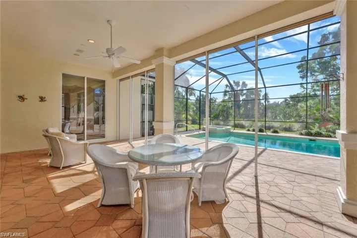 View of patio / terrace with a ceiling fan, a sunroom, a pool with connected hot tub, glass enclosure, and outdoor dining space