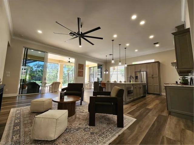 Living room featuring a sunroom, ceiling fan, dark wood-style flooring, ornamental molding, and recessed lighting