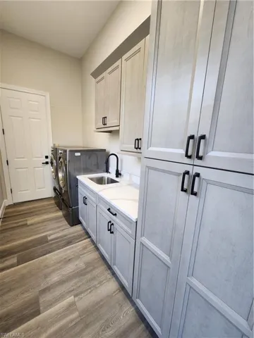 Laundry room featuring cabinet space, dark wood-type flooring, and independent washer and dryer