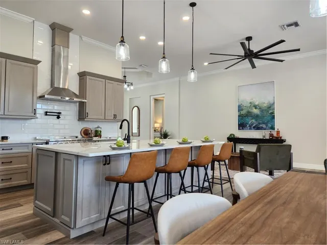 Kitchen featuring ornamental molding, dark wood finished floors, tasteful backsplash, pendant lighting, and a breakfast bar