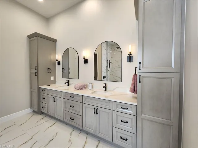 Bathroom with double vanity and light marble finish floors