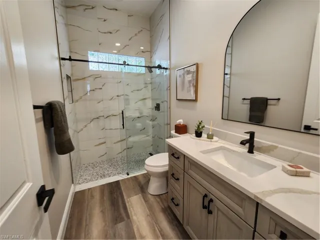 Bathroom with vanity, a marble finish shower, and dark wood finished floors