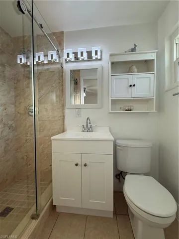 Full bathroom featuring a stall shower, vanity, toilet, and tile patterned floors