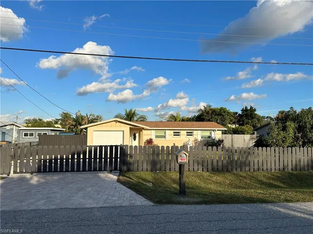 View of front of home with a fenced front yard, decorative driveway, and a garage