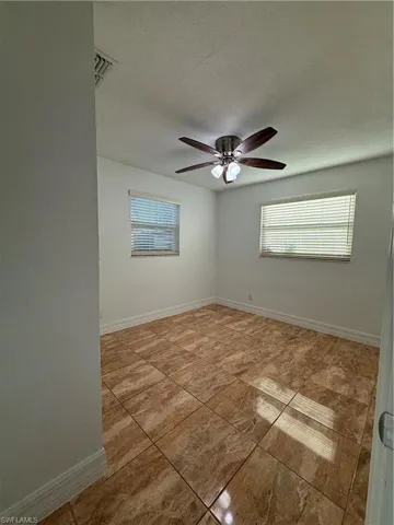 Unfurnished room with a ceiling fan, visible vents, baseboards, and a textured ceiling