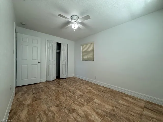 Unfurnished bedroom with a textured ceiling, baseboards, and a closet