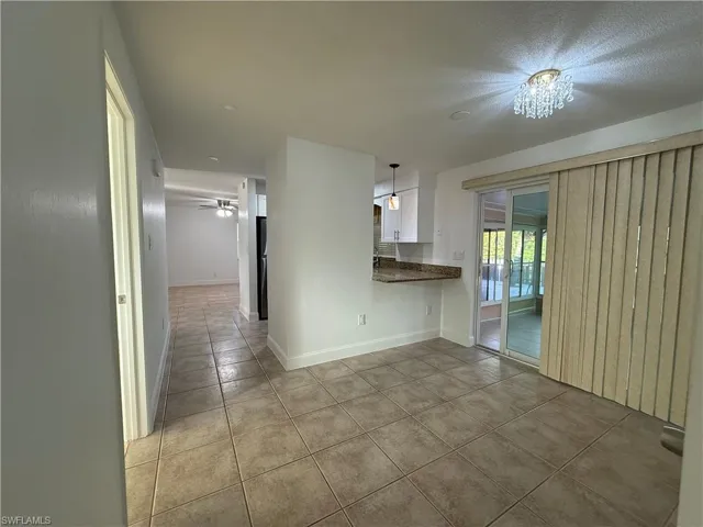 Kitchen with dark countertops, white cabinets, baseboards, and light tile patterned floors