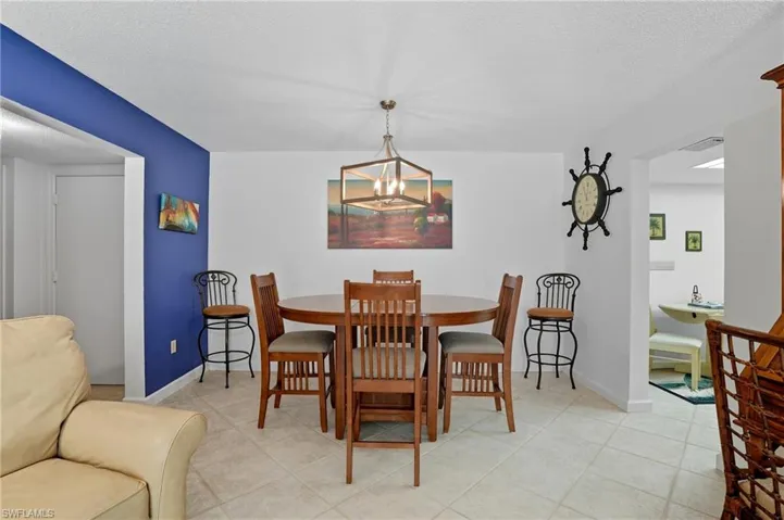 Dining area featuring tile flooring, a contemporary chandelier, and a distinctive accent wall