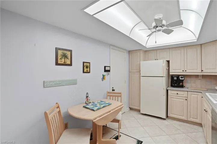Kitchen featuring light wood-finish cabinetry, tile flooring, and a recessed ceiling with a central fan light fixture