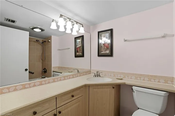 Bathroom featuring a single basin vanity with wood-finish cabinetry, a large wall mirror, and a tiled shower with a sliding door