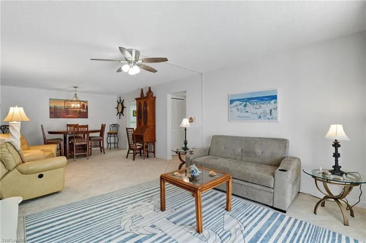 Open-concept living space featuring neutral tone tile flooring and white walls