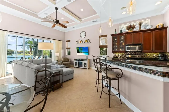 Kitchen featuring a kitchen island, crown molding, coffered ceiling, pendant lighting, and glass insert cabinets