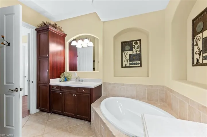 Bathroom featuring vanity, a garden tub, and light tile patterned floors