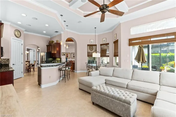 Living area with arched walkways, a ceiling fan, recessed lighting, a high ceiling, and light tile patterned floors