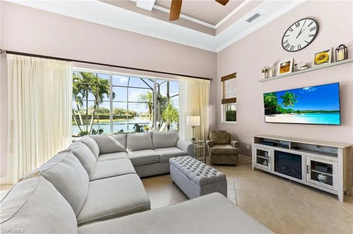 Living room with ceiling fan, light tile patterned floors, ornamental molding and a raised ceiling