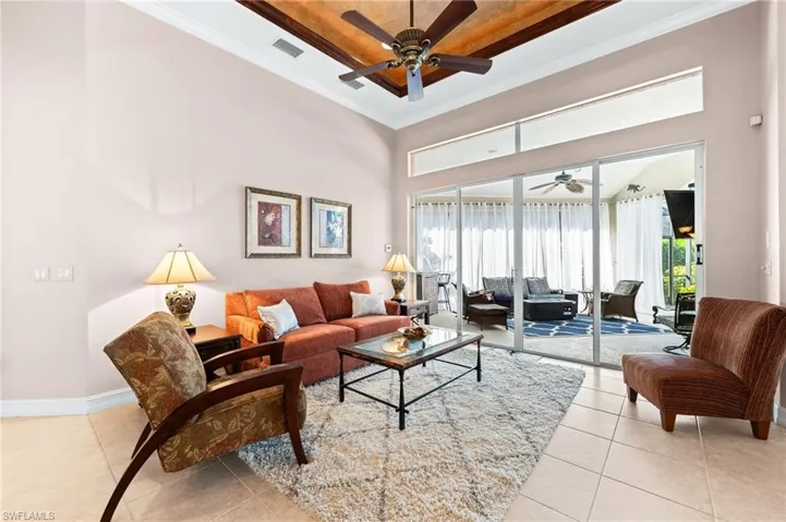 Living area featuring a raised ceiling, a ceiling fan, crown molding, and light tile patterned floors