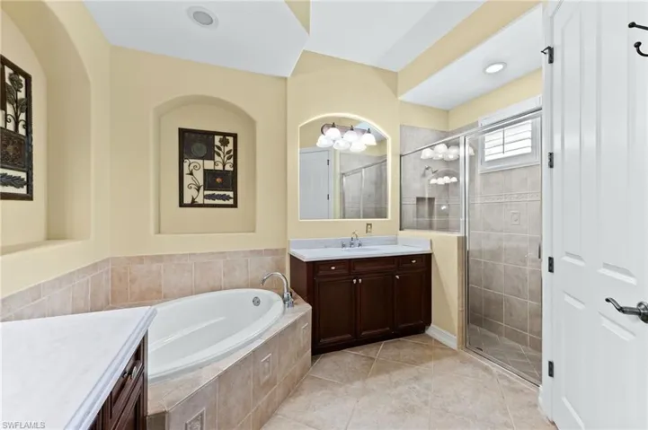 Bathroom with vanity, a garden tub, a stall shower, and light tile patterned flooring
