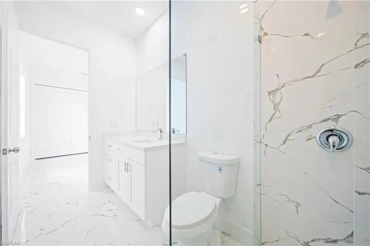 Full bathroom with vanity, light marble finish floors, a marble finish shower, and recessed lighting