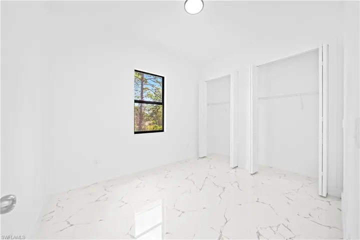Unfurnished bedroom featuring two closets and light marble finish flooring
