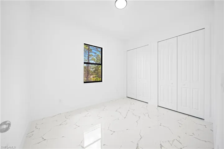 Unfurnished bedroom featuring multiple closets and light marble finish floors