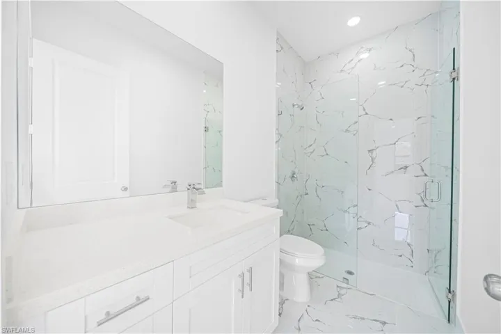 Bathroom featuring a marble finish shower, vanity, recessed lighting, and light marble finish floors