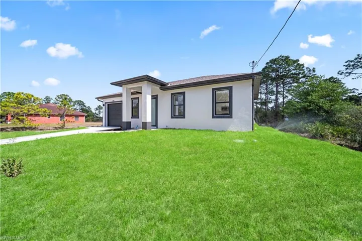 Prairie-style home featuring a front yard, an attached garage, stucco siding, and concrete driveway