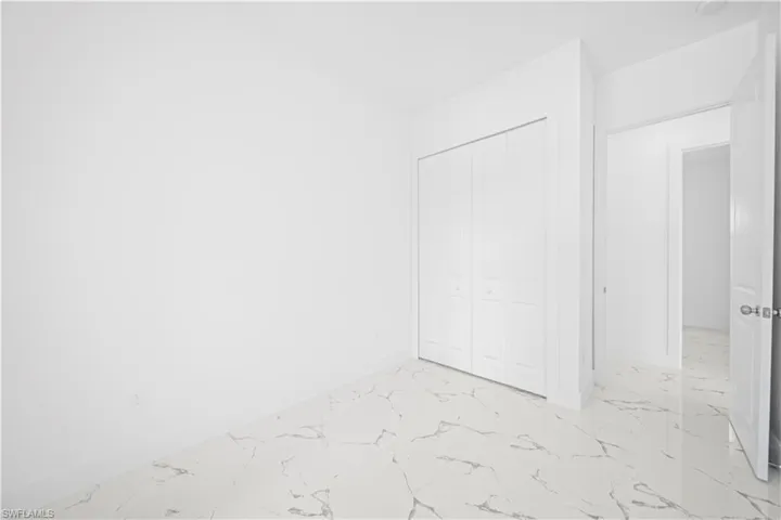 Unfurnished bedroom with light marble finish flooring and a closet