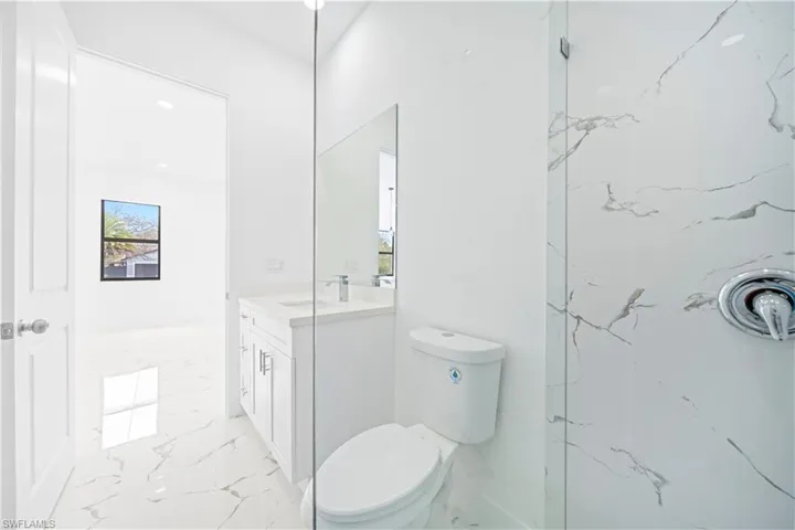 Full bathroom featuring vanity, a marble finish shower, and light marble finish floors