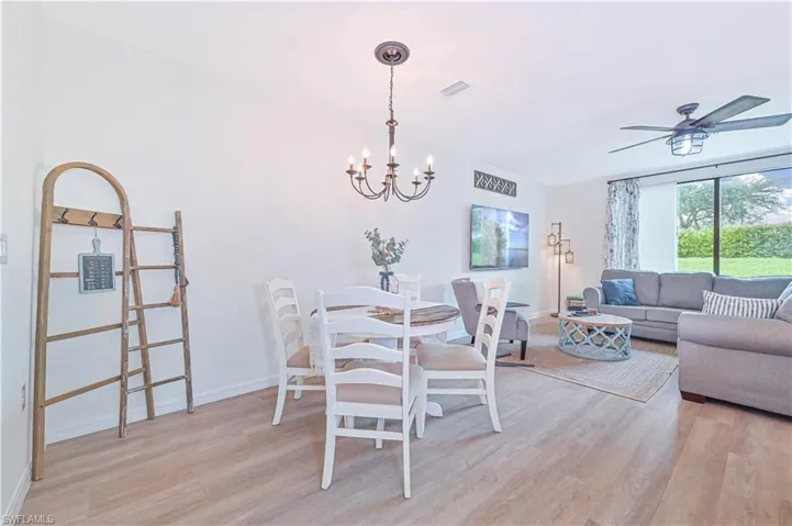 Dining area with ceiling fan with notable chandelier and light wood-type flooring