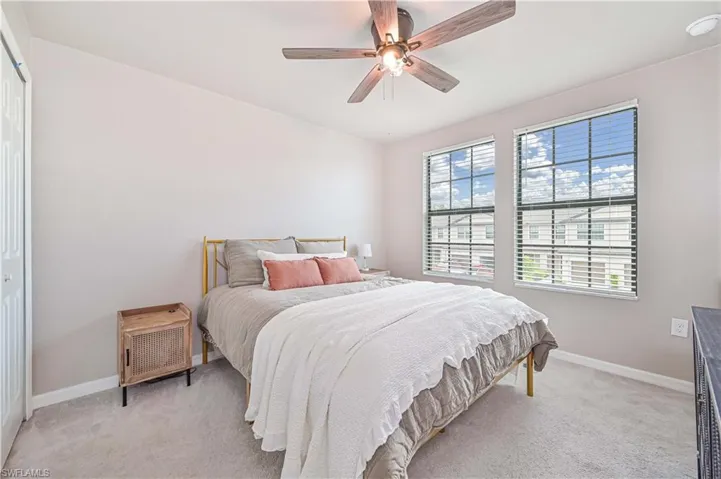 Bedroom featuring ceiling fan, light carpet, and multiple windows