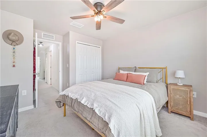 Bedroom featuring a closet, light colored carpet, and ceiling fan