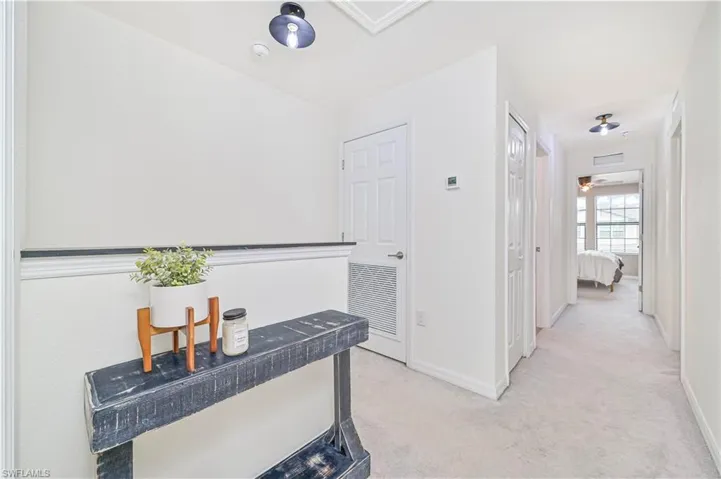 Hallway featuring light carpet