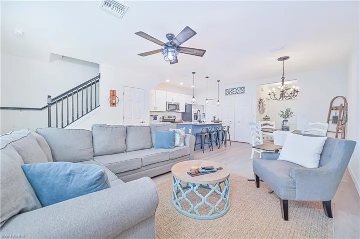 Living room featuring ceiling fan with notable chandelier and light hardwood / wood-style flooring