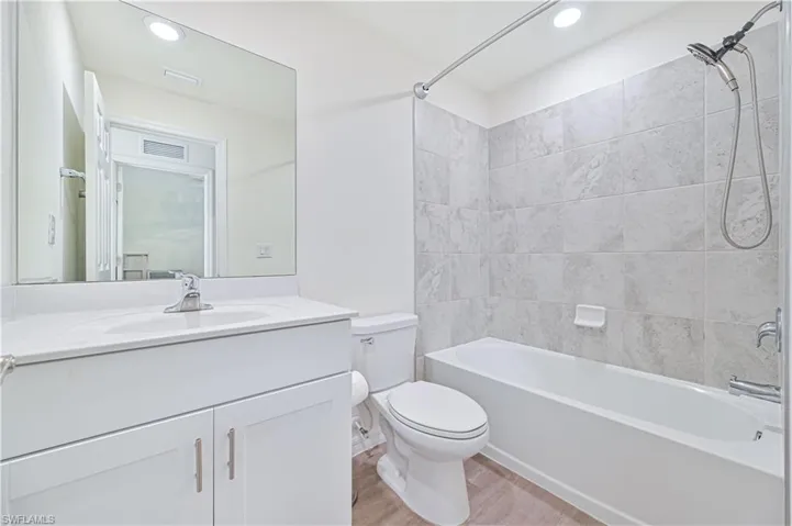 Full bathroom with wood-type flooring, tiled shower / bath, vanity, and toilet