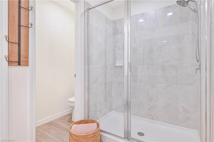 Bathroom featuring an enclosed shower, hardwood / wood-style floors, and toilet