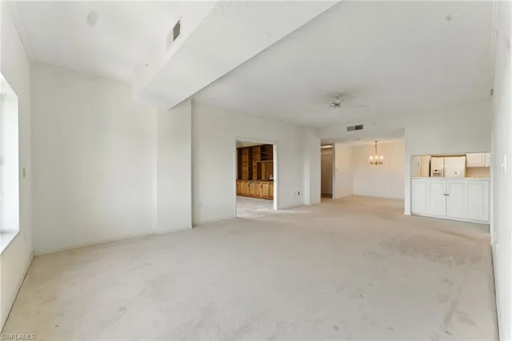 Unfurnished living room with light carpet, ceiling fan, and a chandelier