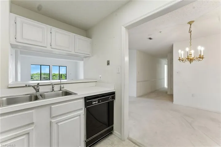 Kitchen featuring white cabinets, light countertops, black dishwasher, a chandelier, and a textured ceiling