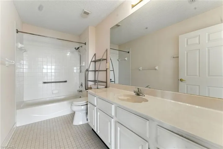 Bathroom with vanity, shower / washtub combination, light tile patterned flooring, and a textured ceiling