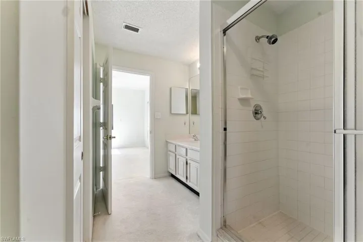 Full bath featuring vanity, a stall shower, and a textured ceiling