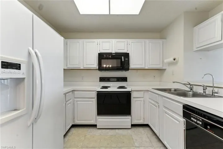 Kitchen featuring black appliances, light countertops, and white cabinetry