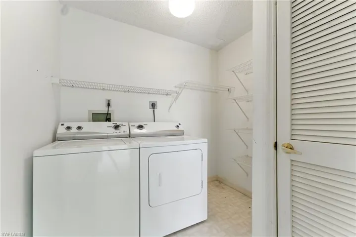 Laundry room with a textured ceiling, light flooring, and washer and dryer