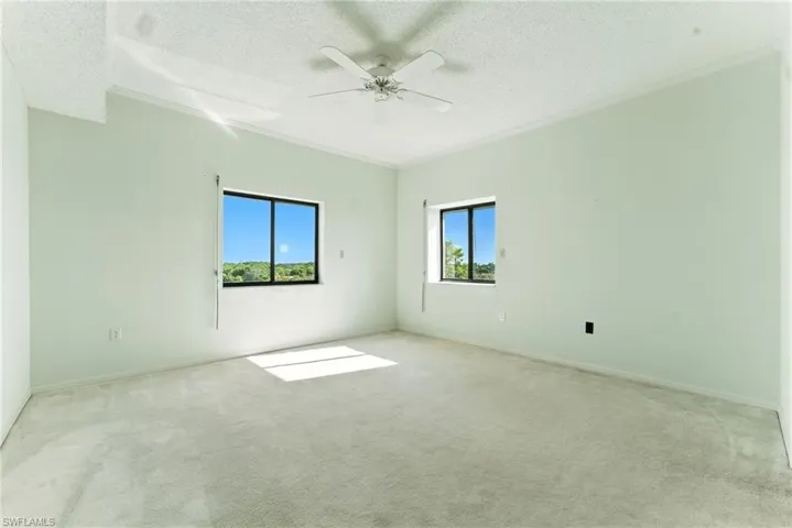 Empty room featuring carpet floors, a textured ceiling, a ceiling fan, and ornamental molding