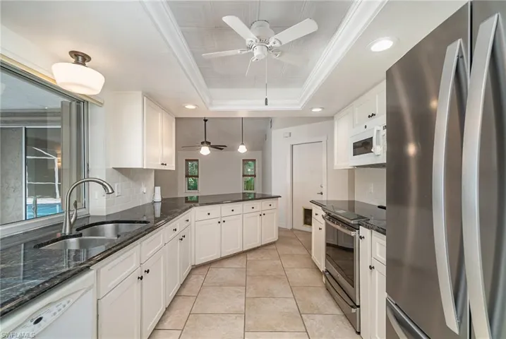 Long upgraded galley kitchen with granite countertops and stainless appliances.