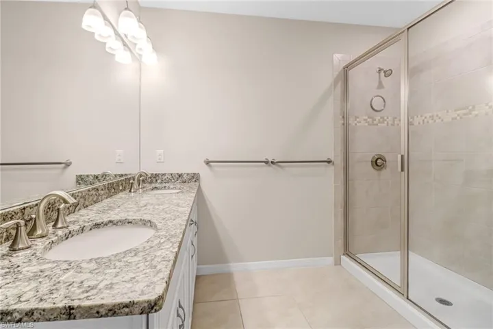 Bathroom featuring dual vanity, an enclosed shower, and tile floors