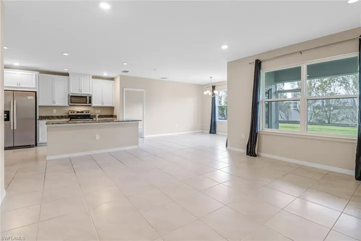 Kitchen featuring stone counters, light tile floors, a kitchen island with sink, white cabinetry, and appliances with stainless steel finishes