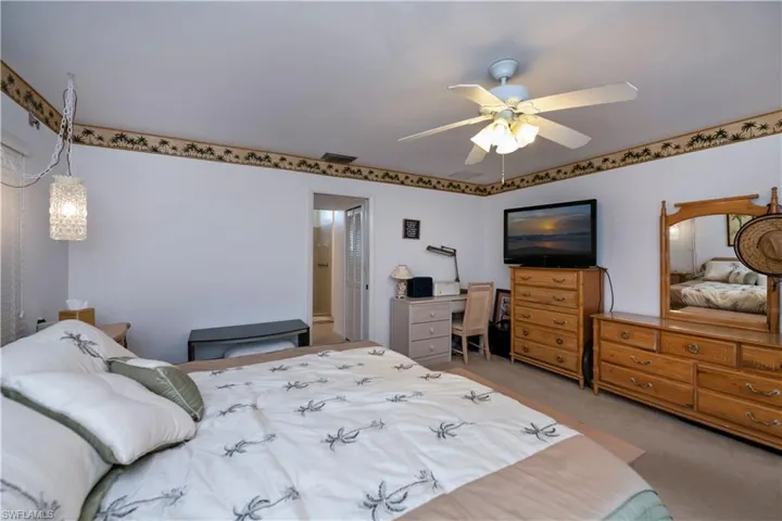 Bedroom featuring ceiling fan, carpet floors, and walk in closets, with access to screened pool lanai